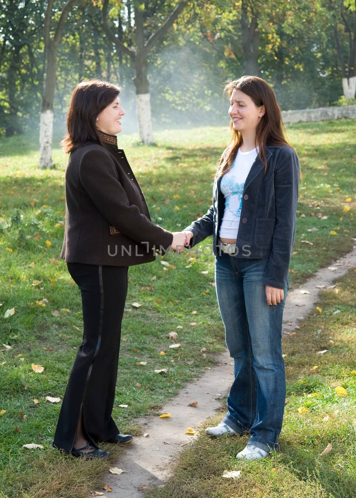 Greeting. Two young beautiful women against park.