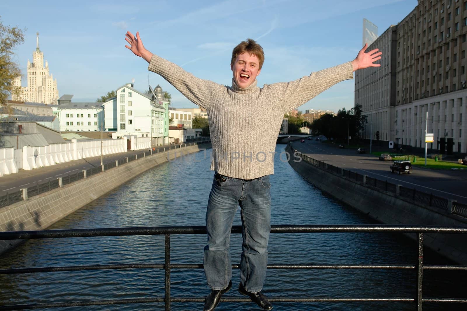 Loud shout. The young man against the river in Moscow.