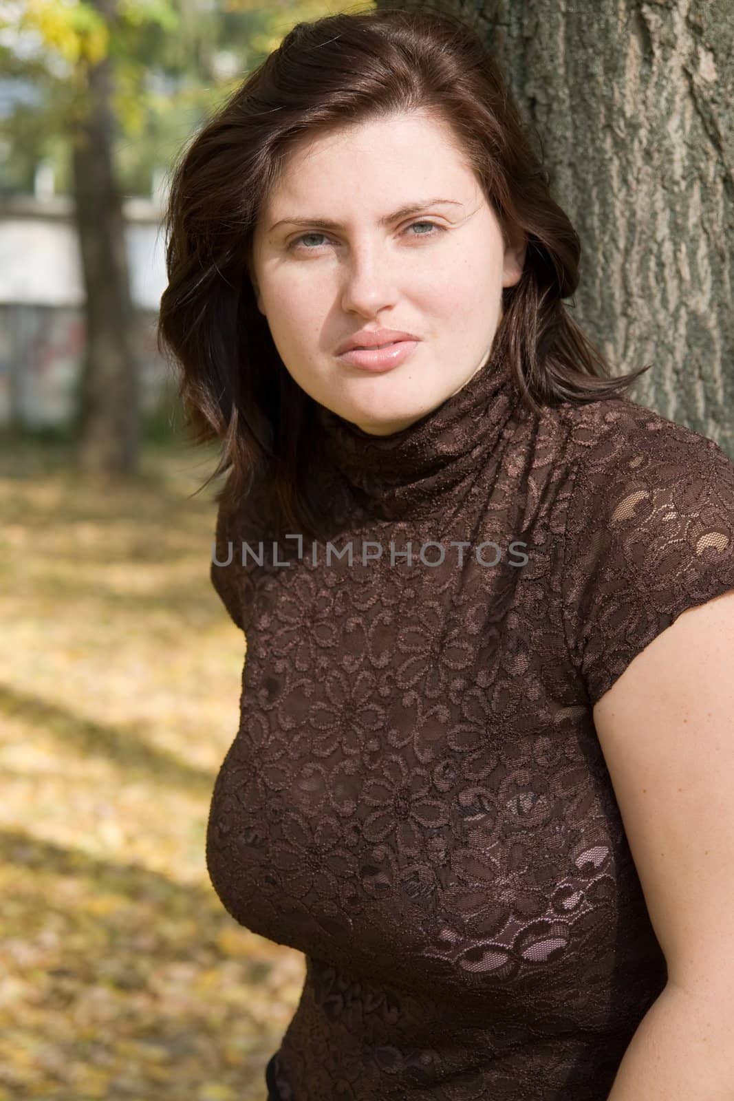 The young beautiful woman near a tree in autumn park.
