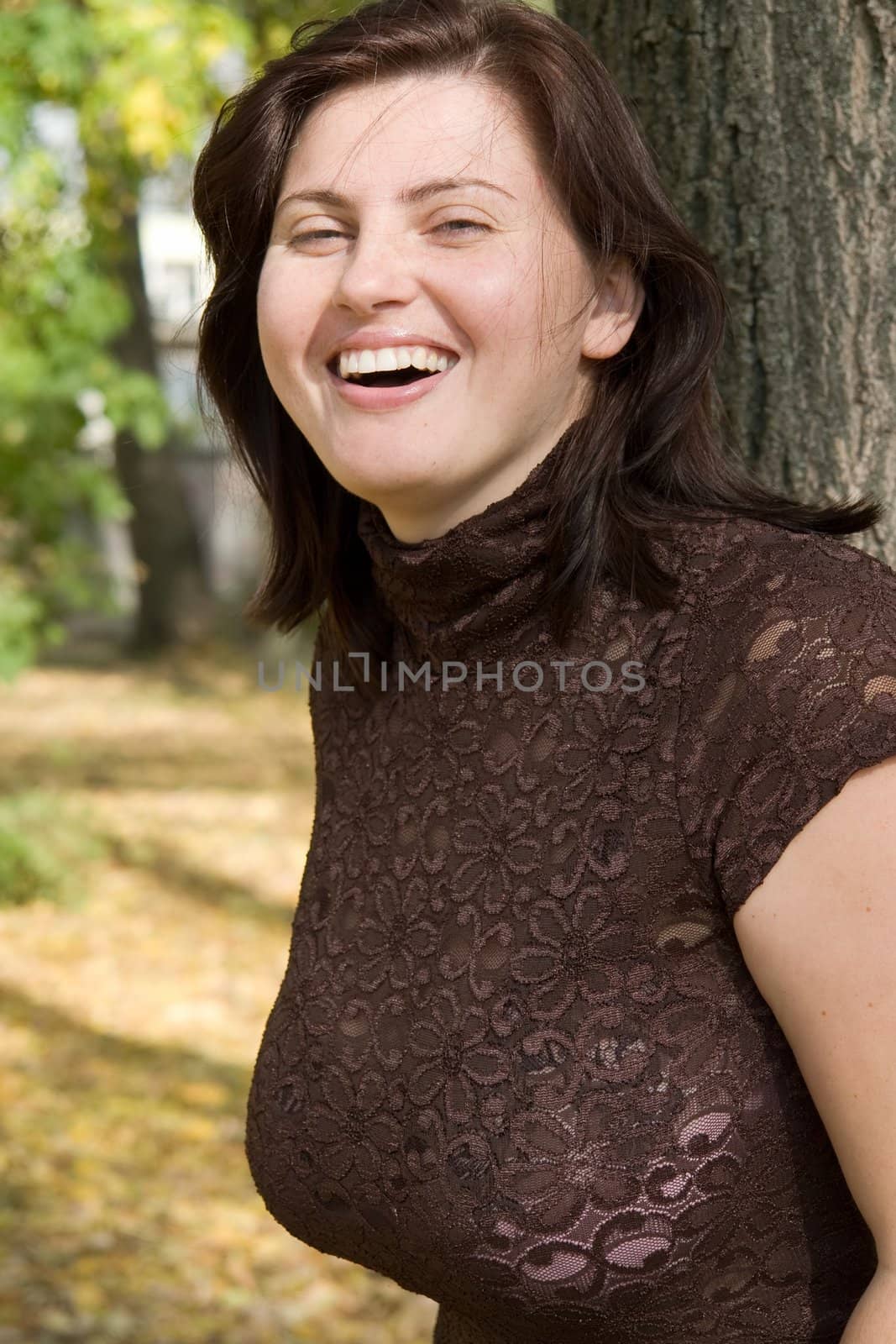 Smiling beautiful woman near a tree in autumn park.