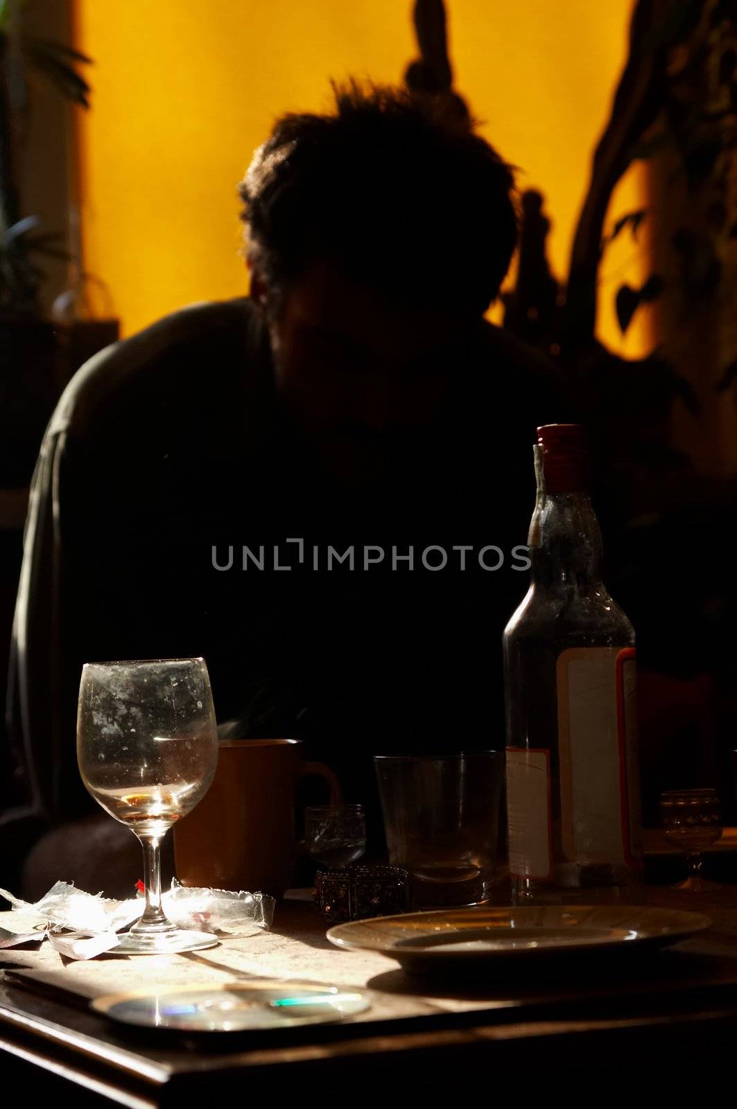 Morning. Man sits at table and smoks cigatrett, near stands  bottle of vodka and glass
