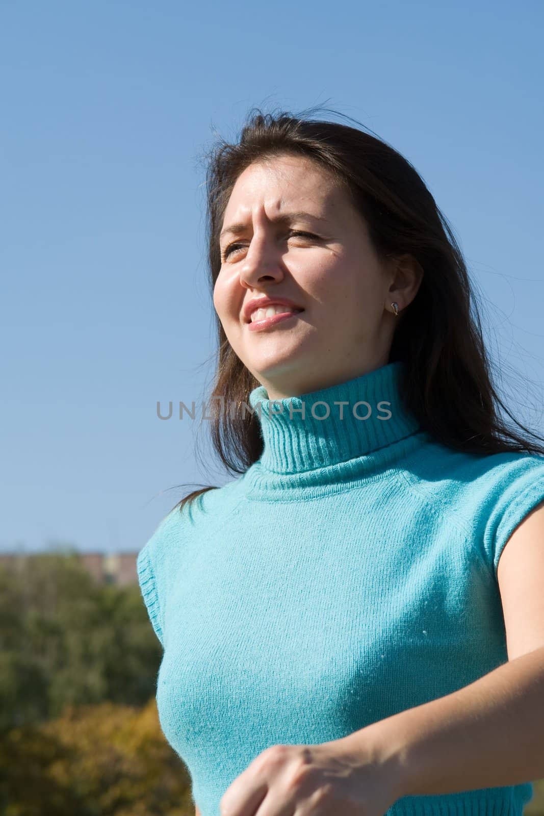 The young beautiful woman walks with blue sky at background