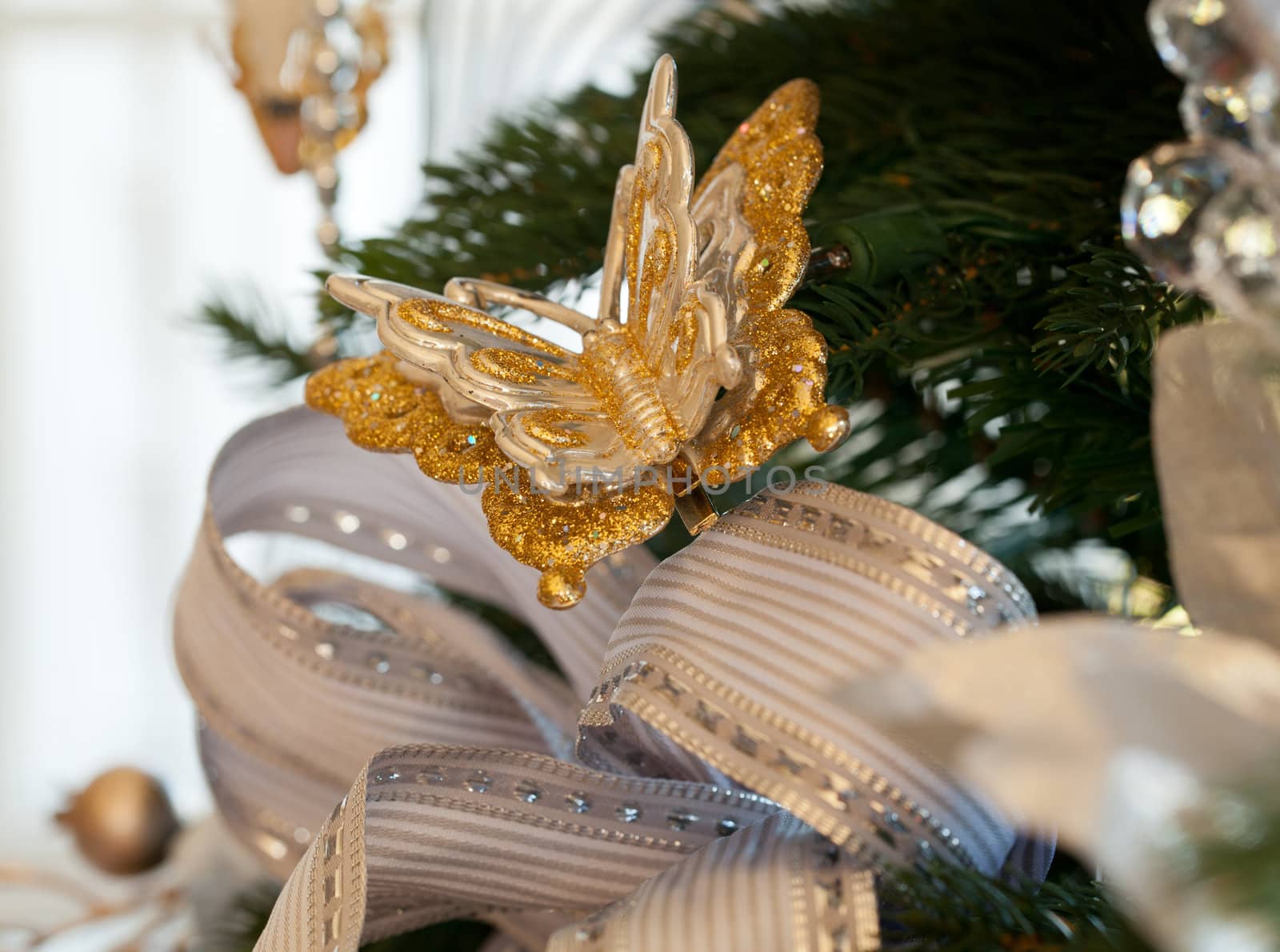 Christmas tree decorated with silver and white ribbons and butterfly ornaments in family home