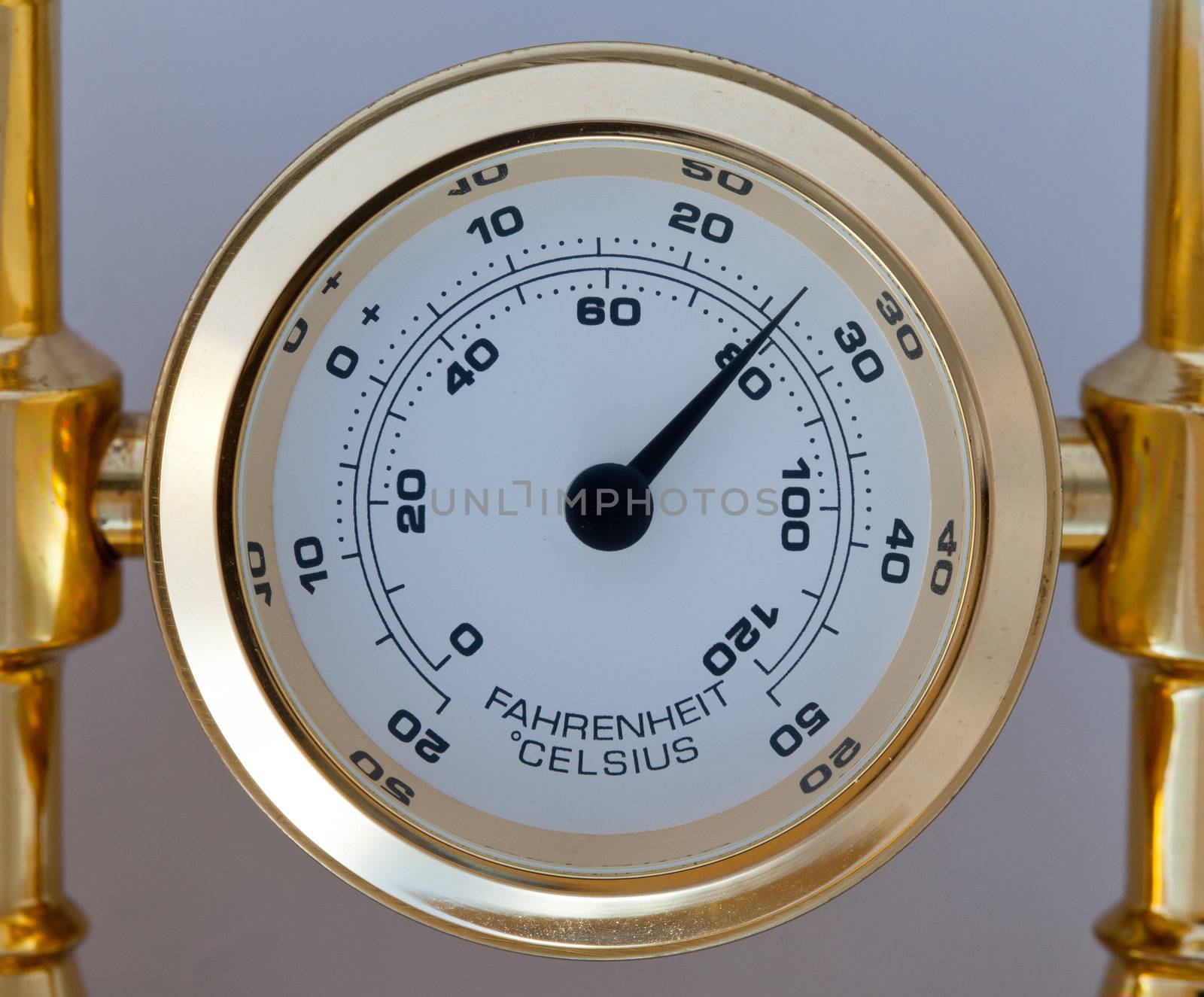 Gold thermometer measuring centigrade and farenheit and fixed in a brass holder