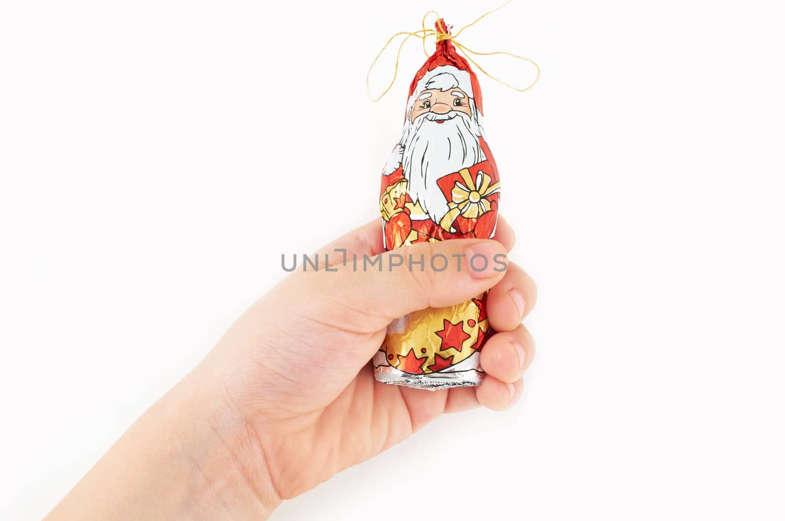 Children's hand holding a Christmas decoration in the form of a chocolate Santa Claus figures on an isolated white background
