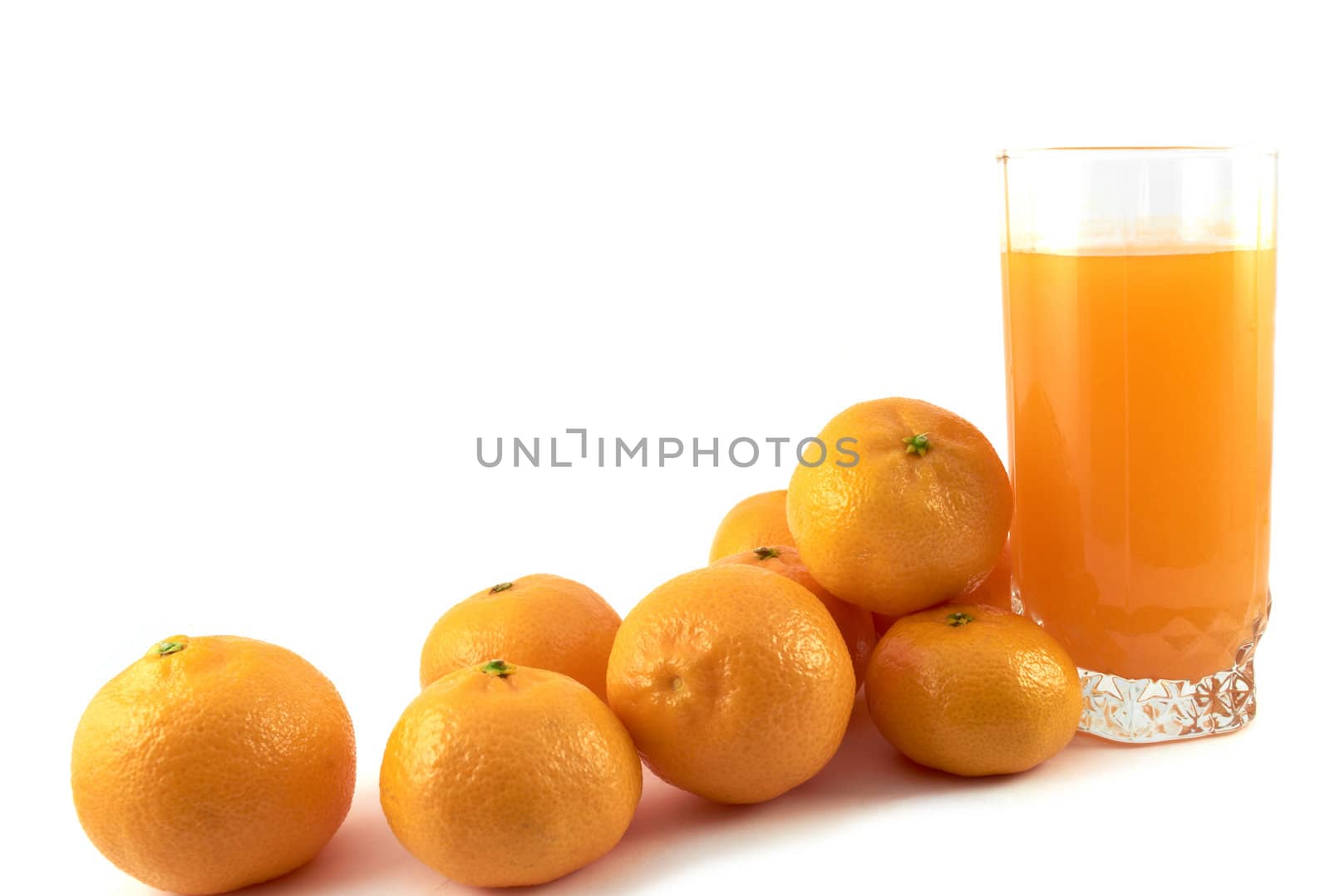 Tangerines and a glass of tangerine juice on a white background