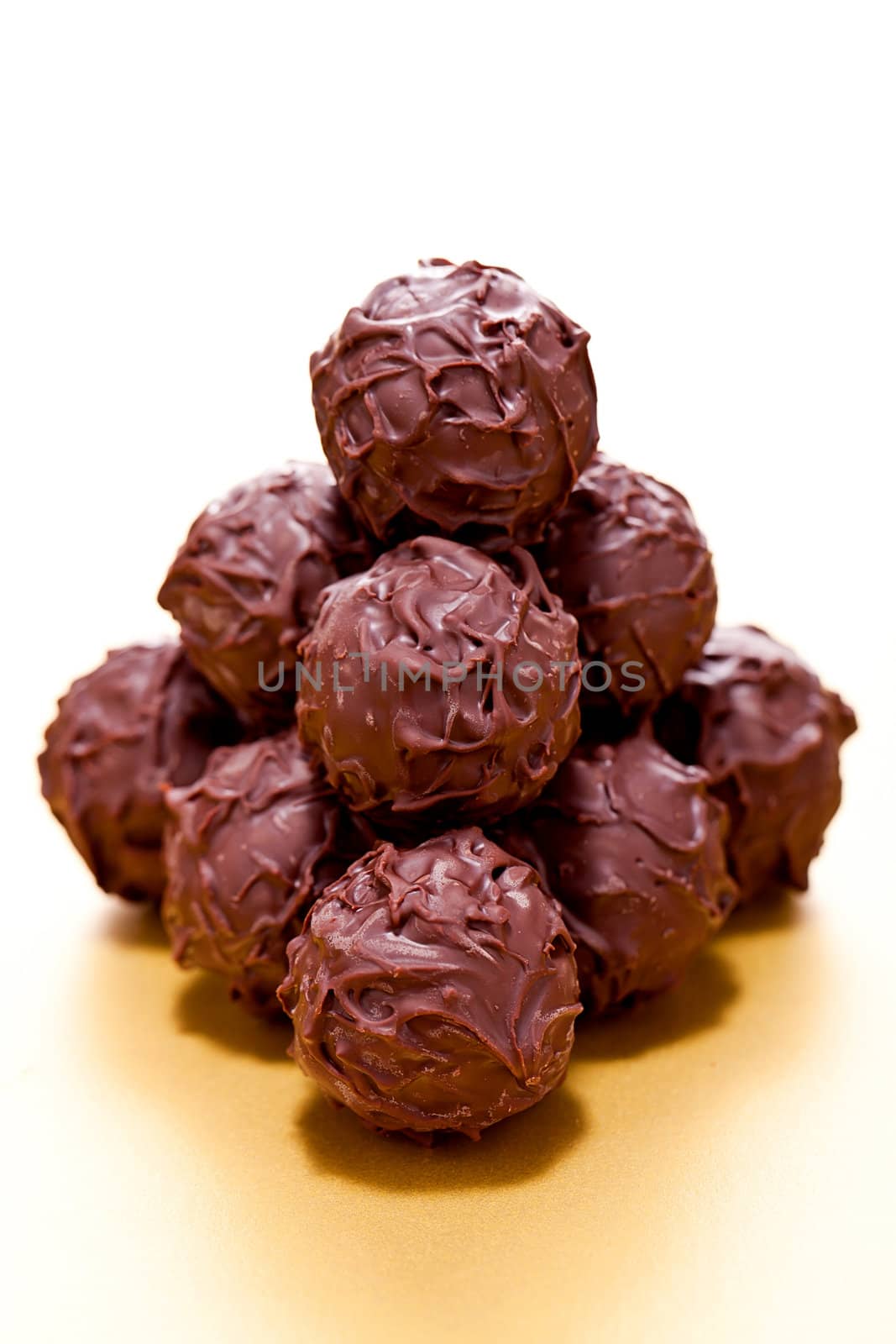 collection of different chocolate pralines truffels on golden brown background macro
