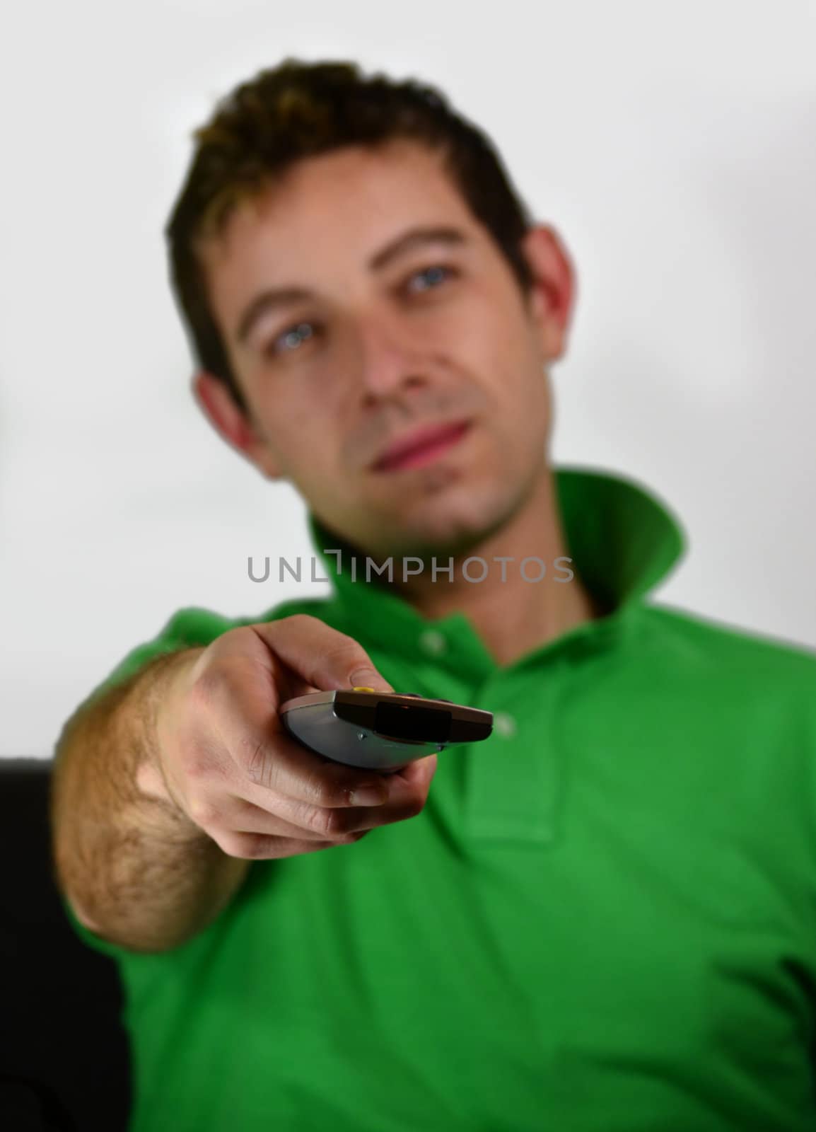 Attractive young man sitting on a couch watching television