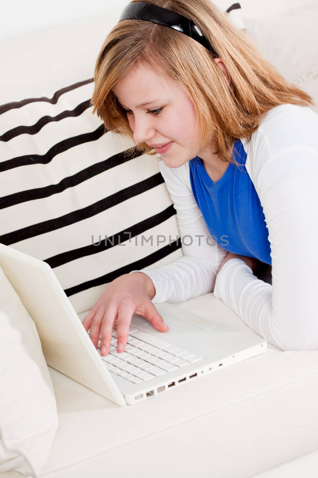 young teenager girl with laptop smilig ssitting on couch 