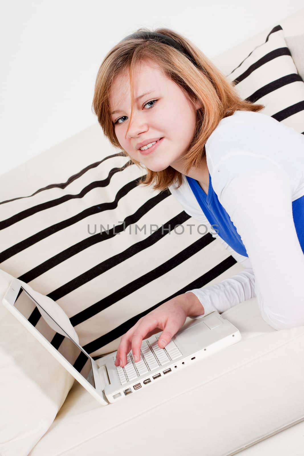 young teenager girl with laptop smilig ssitting on couch 