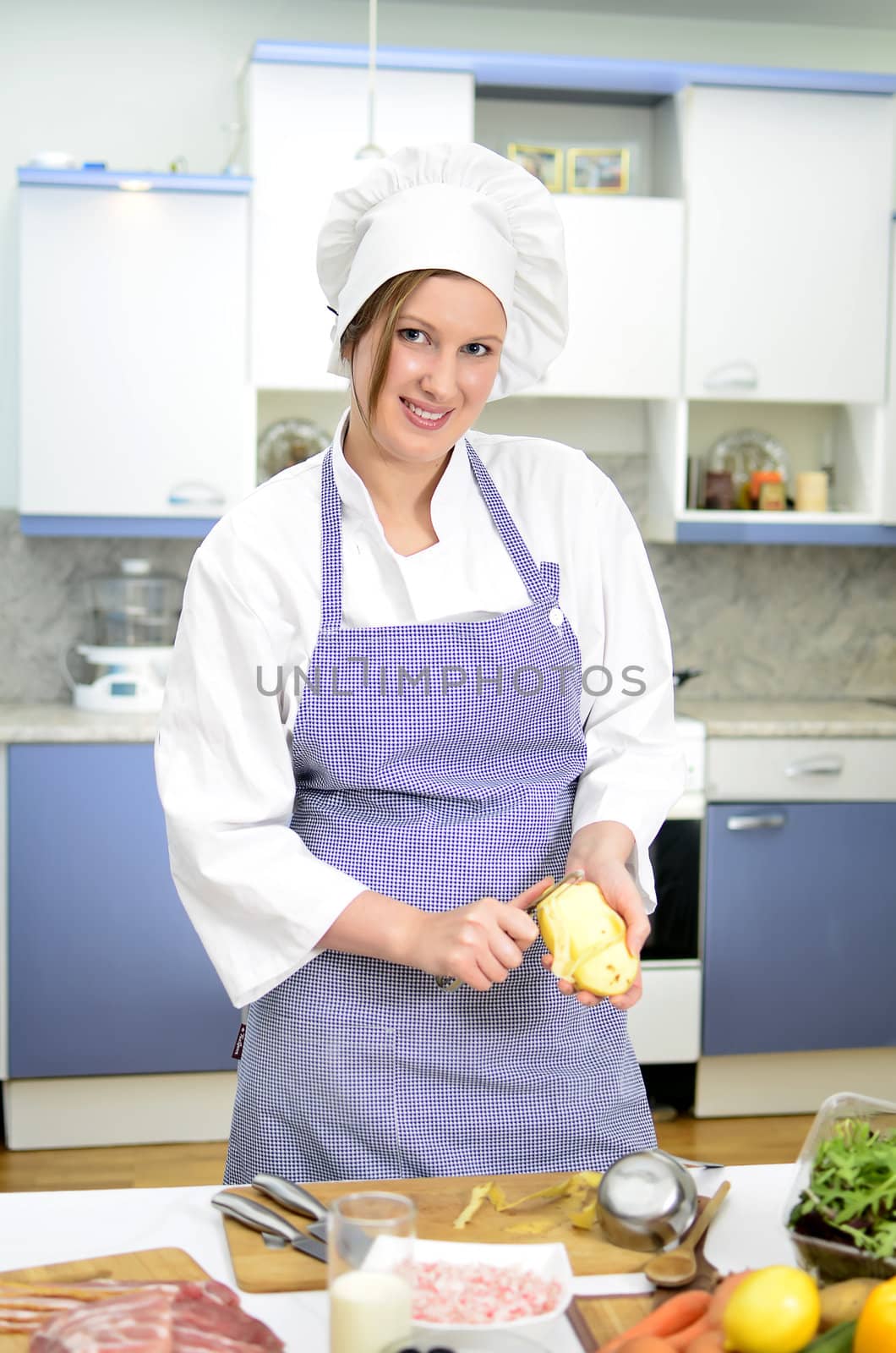 Attractive smiling chief cook preparing food, peeling potatoes