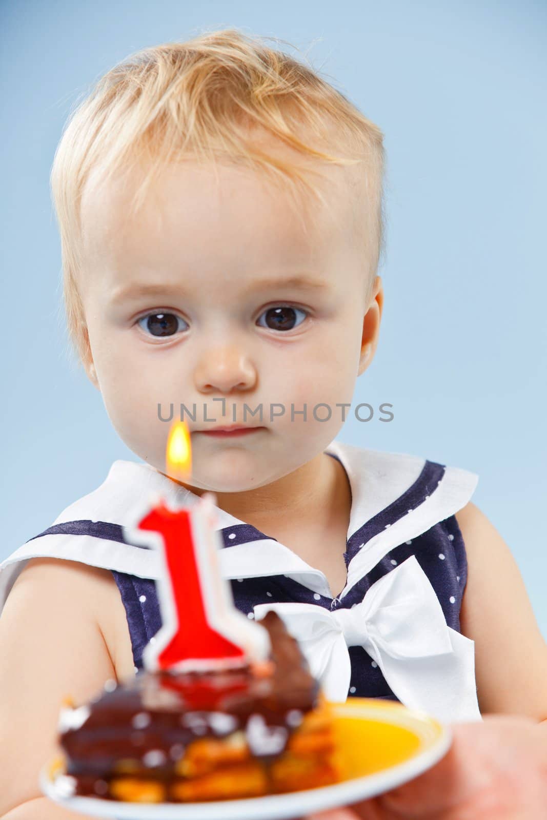 A little sweet girl with a cake and a candle in her first birthday.