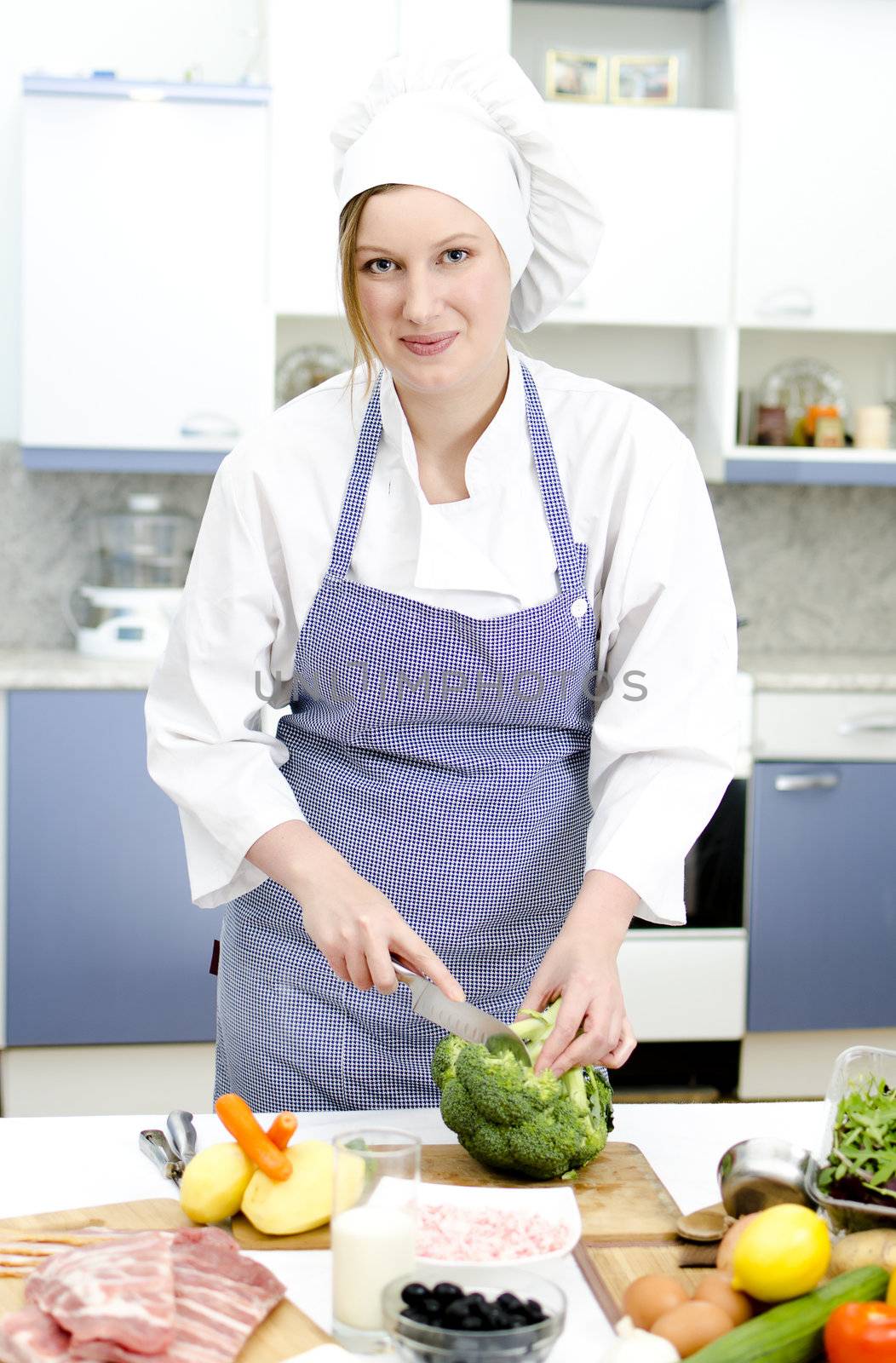 Attractive chief cook preparing food, cuts broccoli
