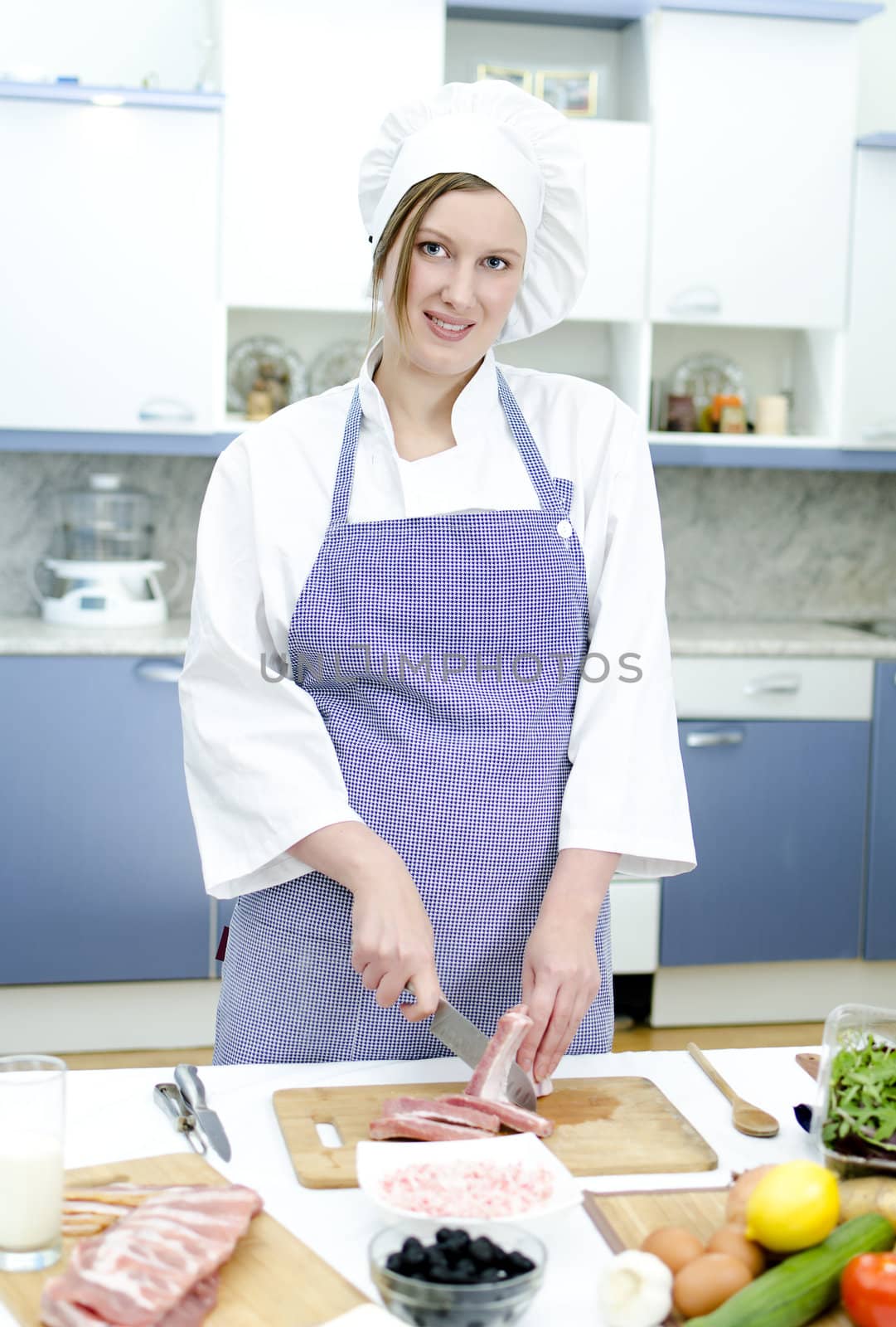 Attractive chief cook preparing food, cutting the meat ribs
