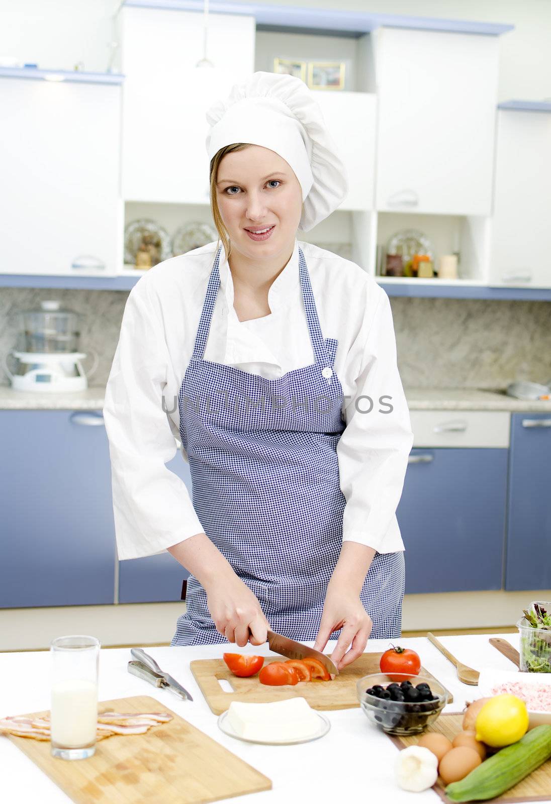 Attractive chief cook preparing food, cutting tomatoes