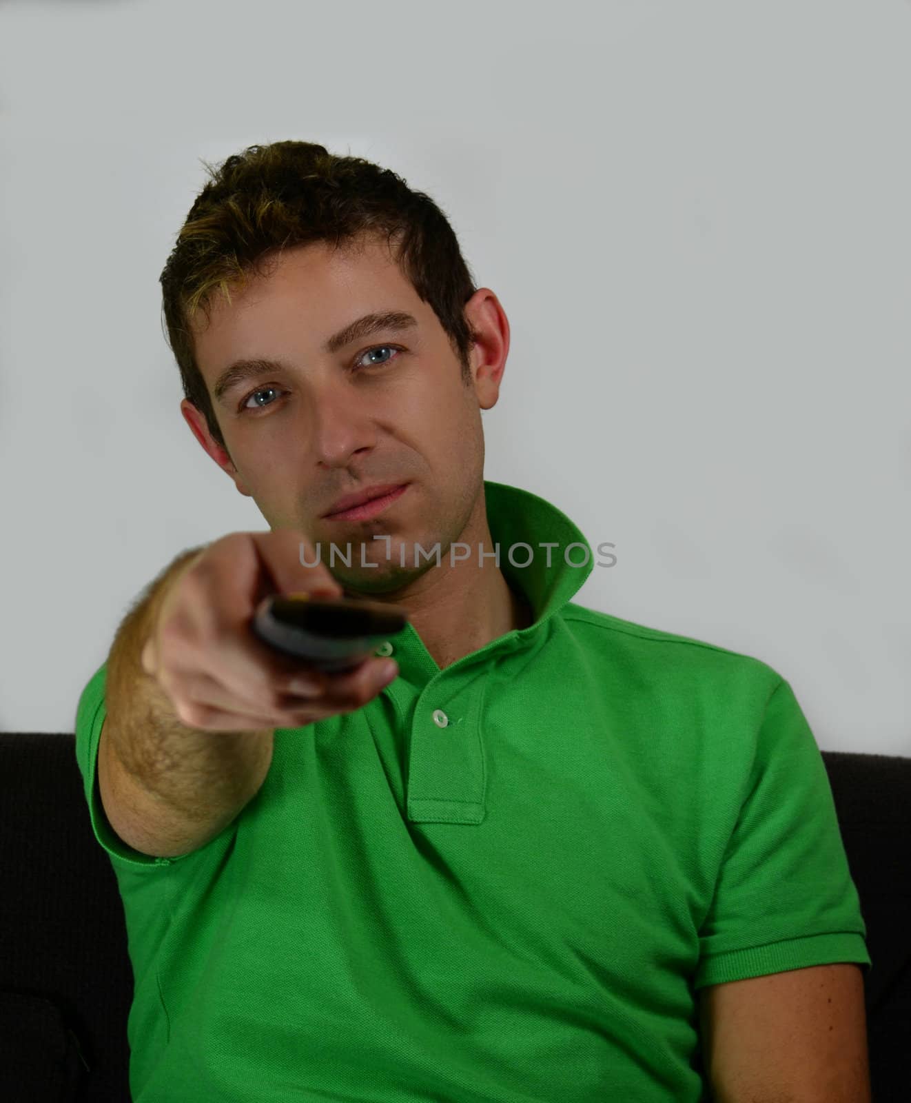 Attractive young man watching TV pointing remote control by artofphoto