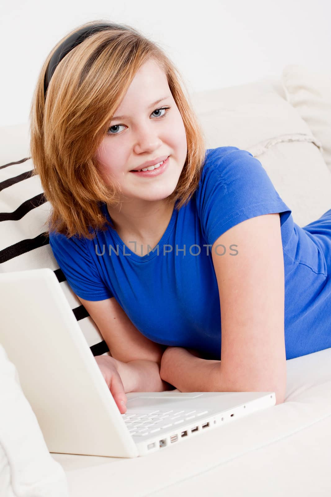 young teenager girl with laptop smilig ssitting on couch 