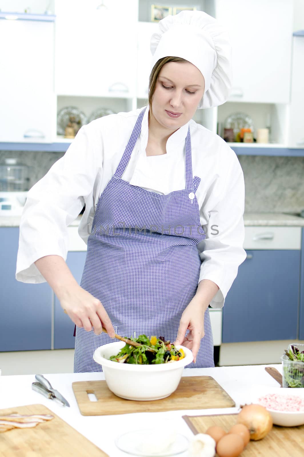 Attractive chief cook preparing salad
