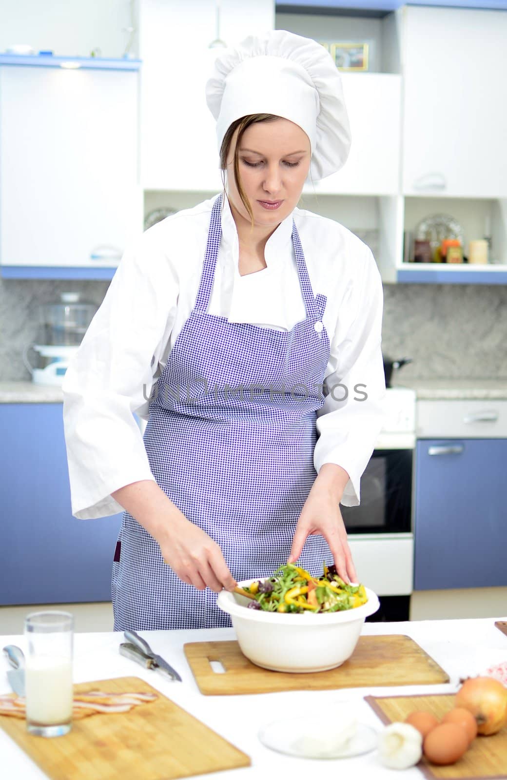 Attractive chief cook preparing salad
