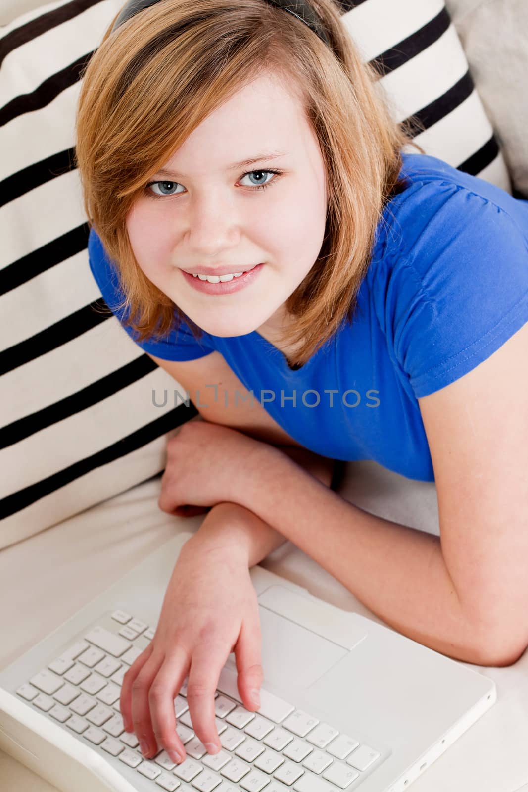 young teenager girl with laptop smilig ssitting on couch 