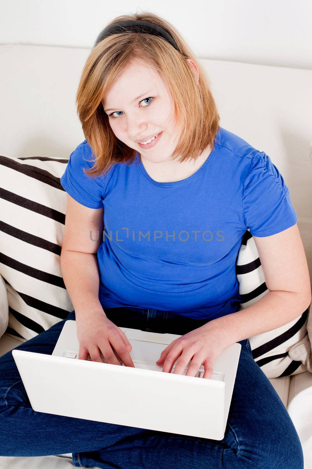 young teenager girl with laptop smilig ssitting on couch 