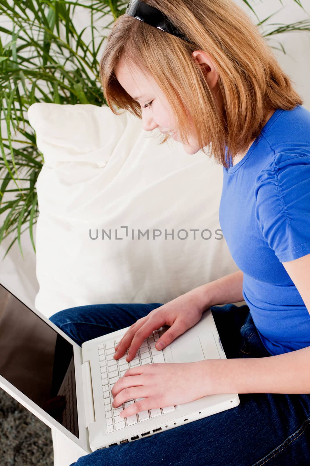 young teenager girl with laptop smilig ssitting on couch 