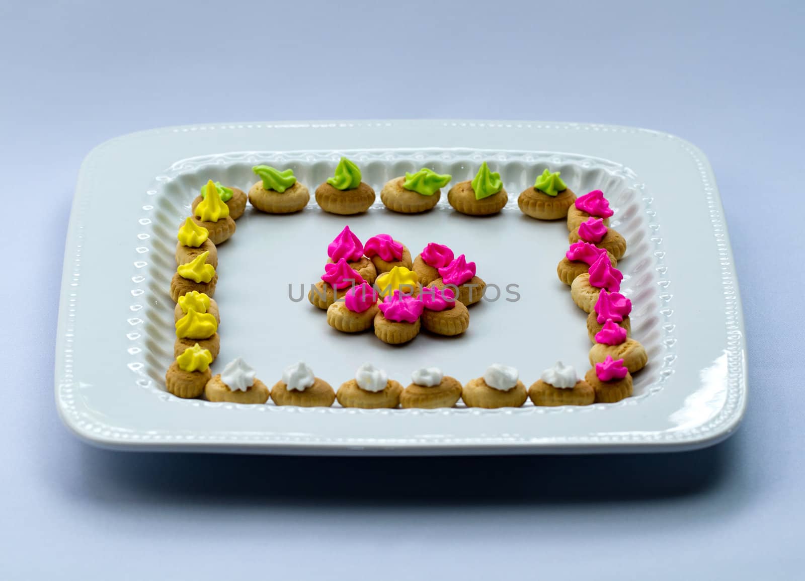 An arrangement of colorful icing topped cookies in white plate
