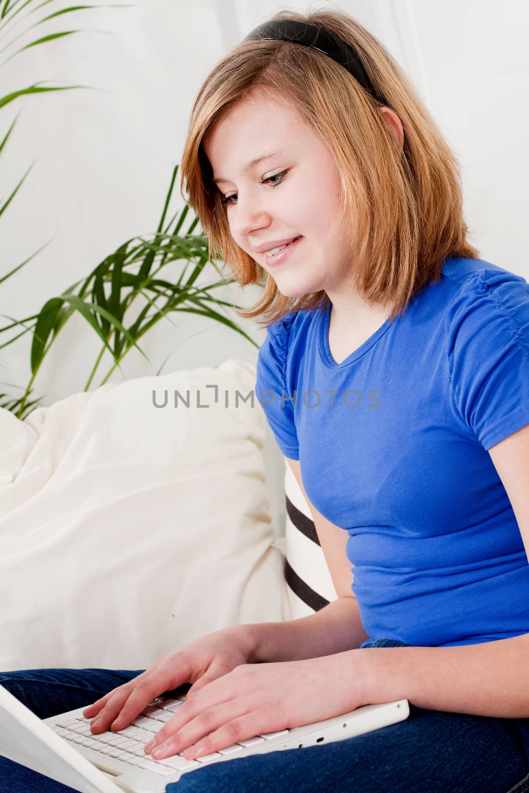 young teenager girl with laptop smilig ssitting on couch 