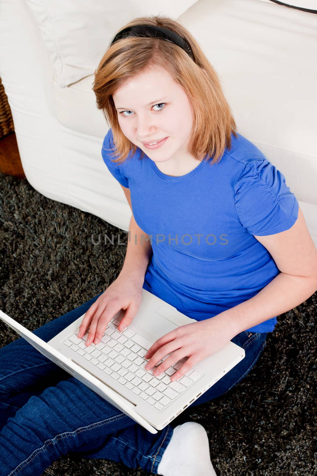 young teenager girl with laptop smilig ssitting on couch 