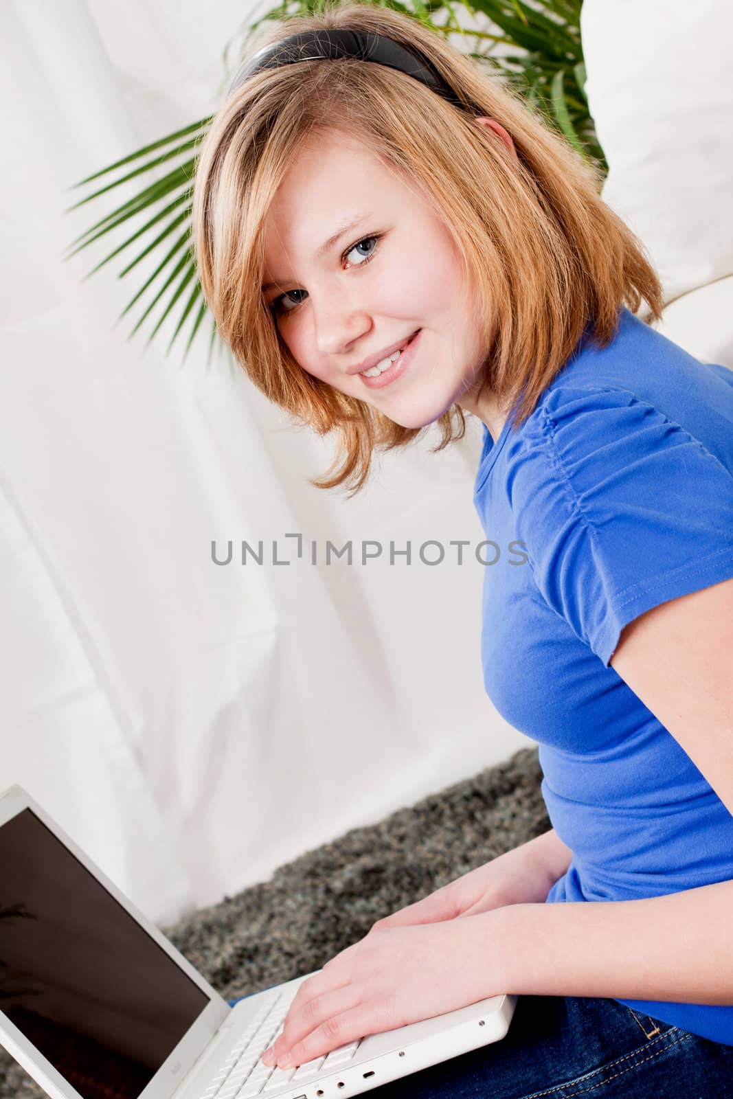 young teenager girl with laptop smilig ssitting on couch 