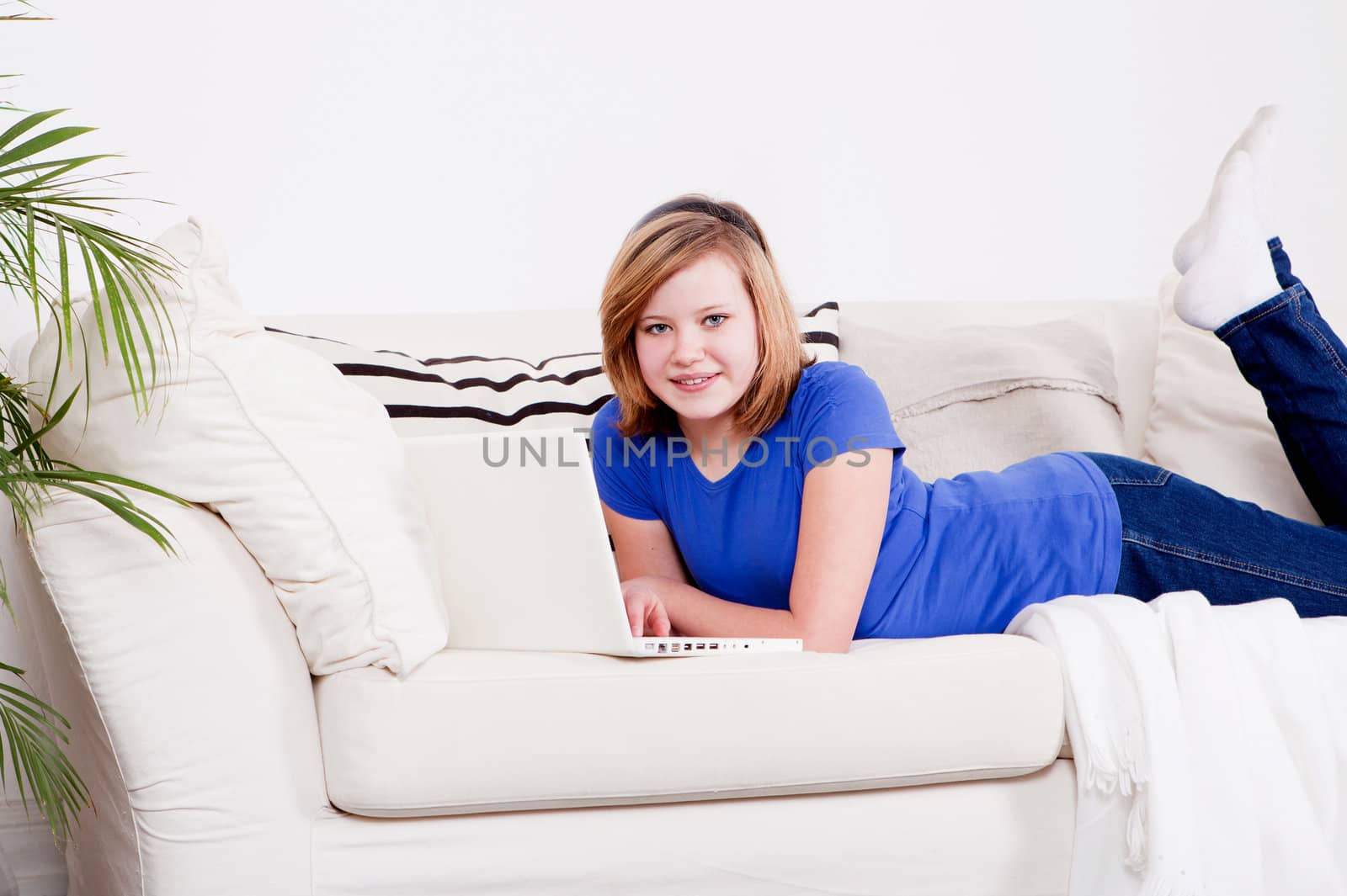 young teenager girl with laptop smilig ssitting on couch 