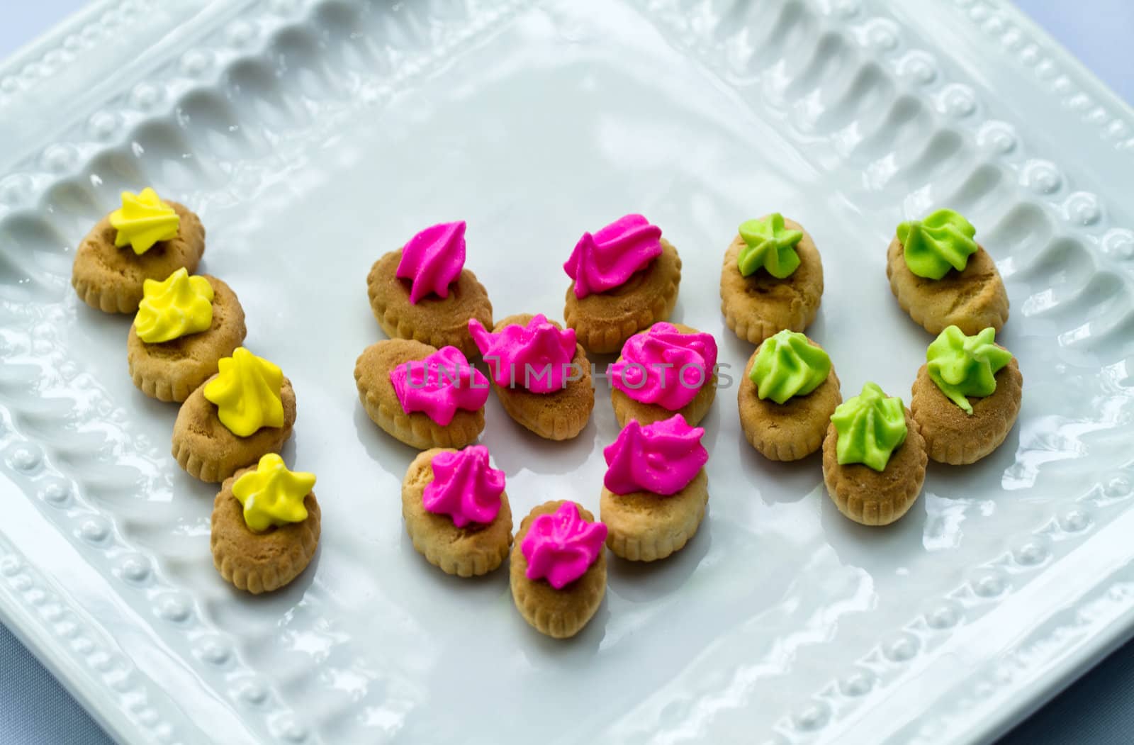 An arrangement of colorful icing topped cookies in white plate making the words 'I Love You"