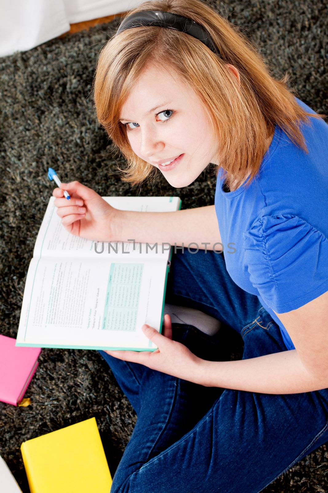 teenager girl sitting on the floor with lot of books and doing homework learning reading