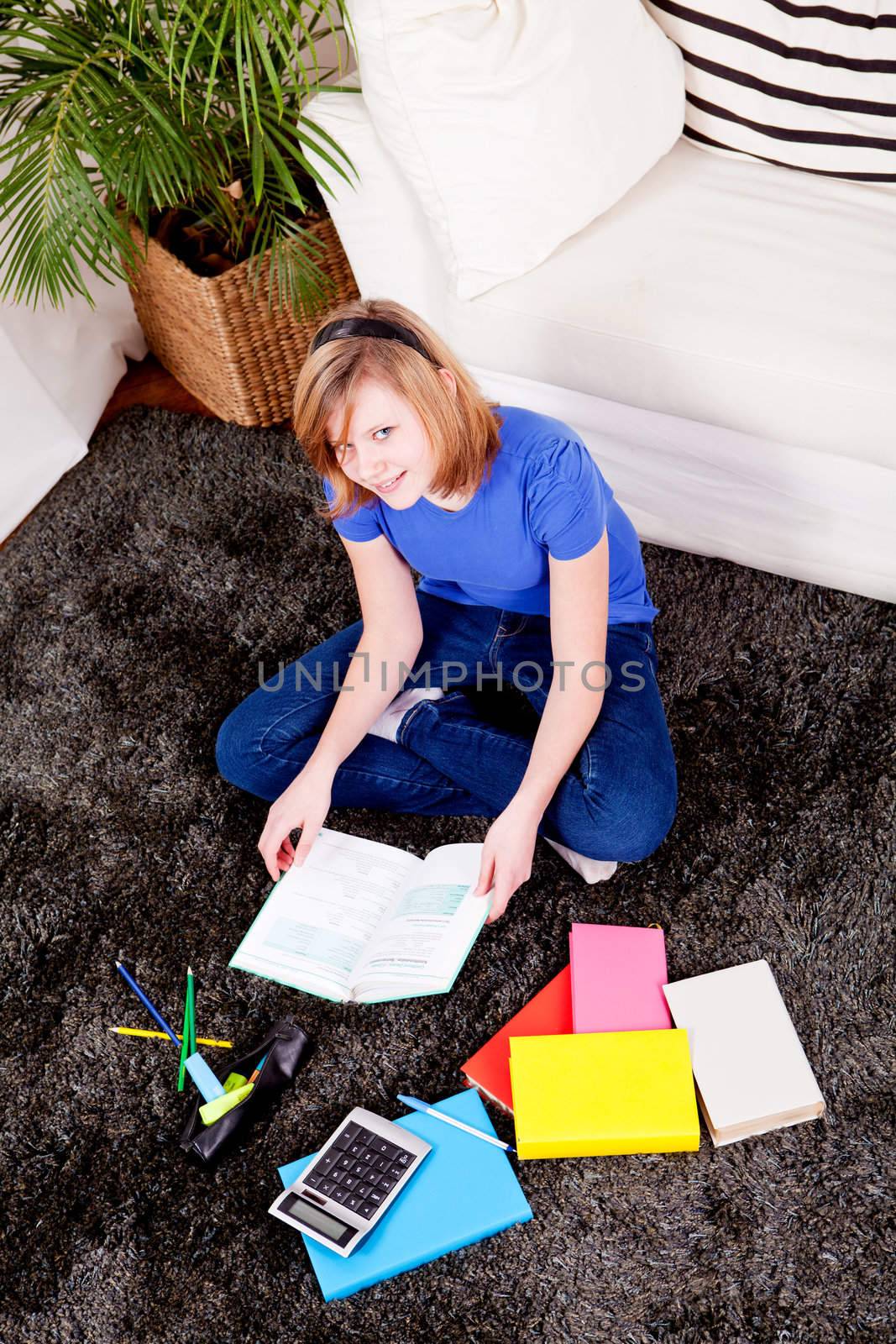 teenager girl sitting on the floor with lot of books and doing homework learning reading