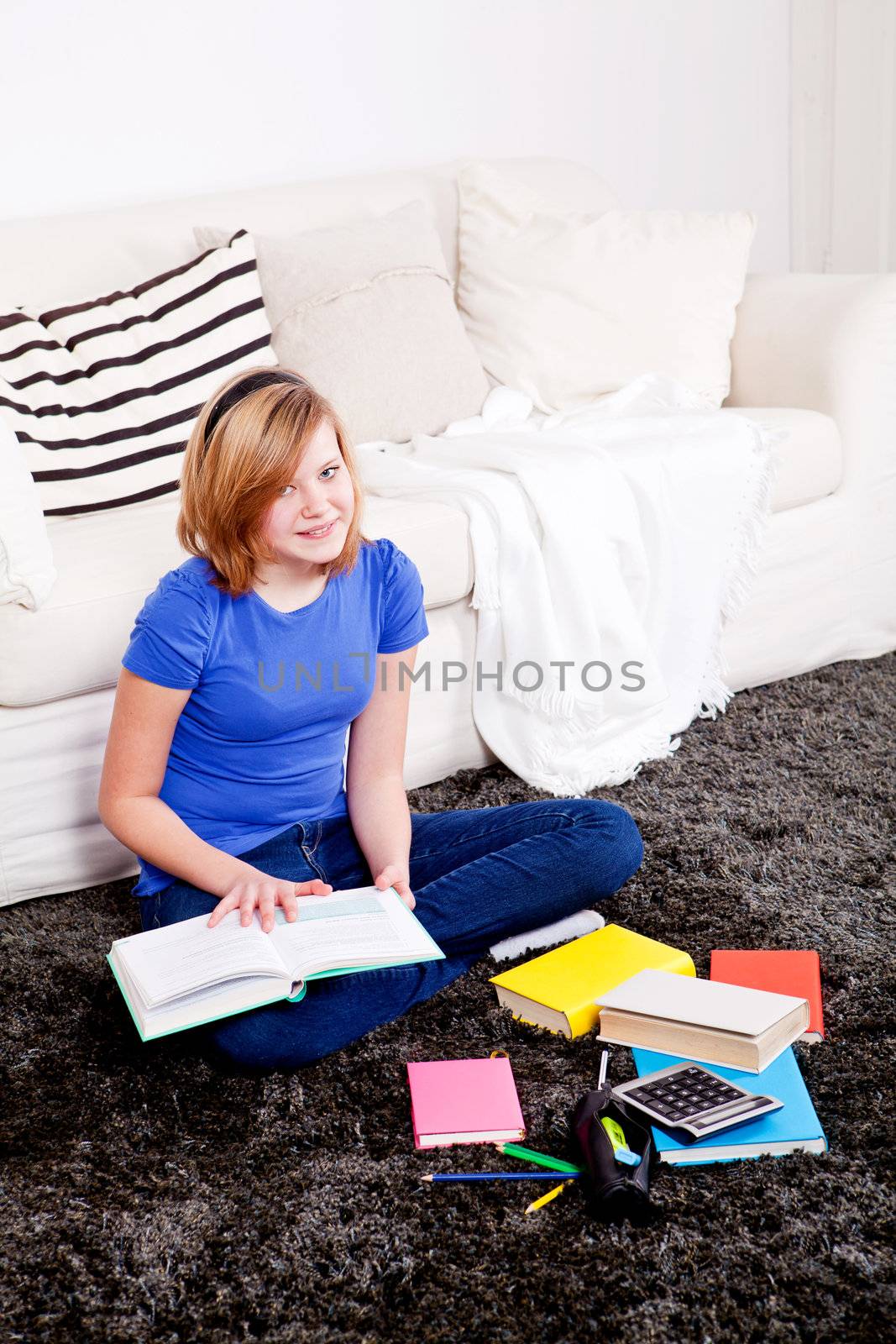 teenager girl sitting on the floor with lot of books and doing homework learning reading