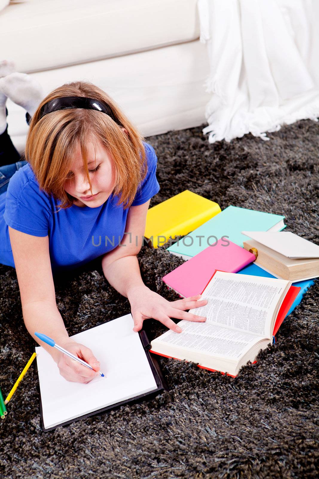 teenager girl sitting on the floor with lot of books and doing homework learning reading