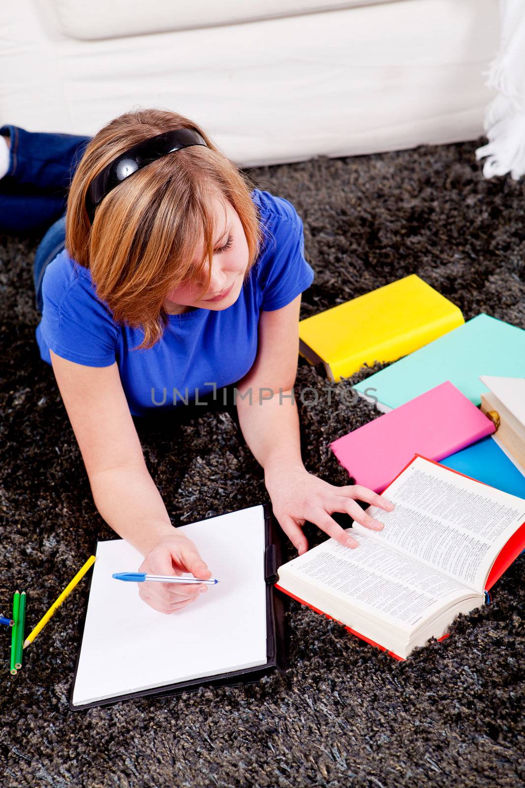 teenager girl sitting on the floor with lot of books and doing homework learning reading