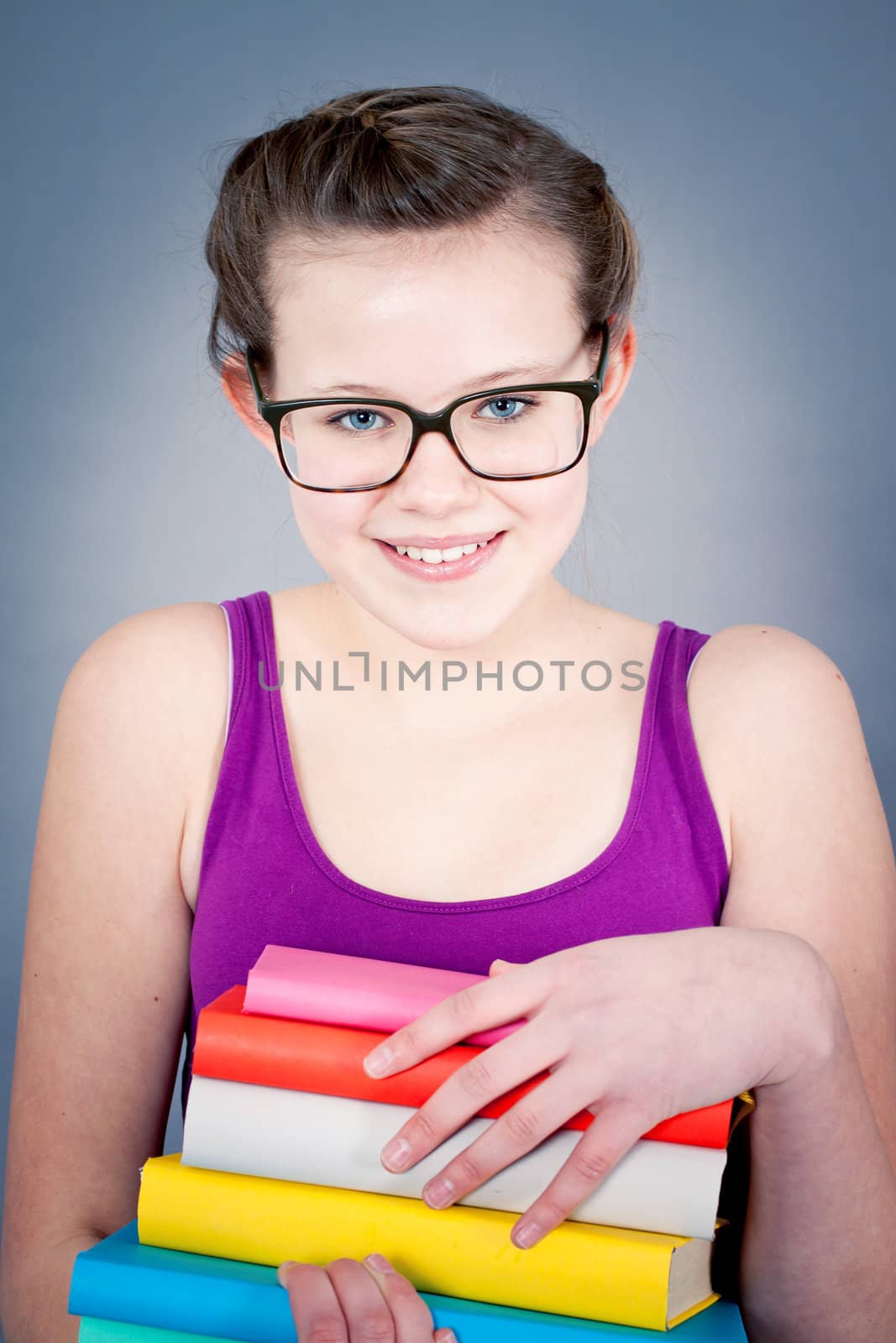 Silly smiling schoolgirl with glasses and lots of books having fun