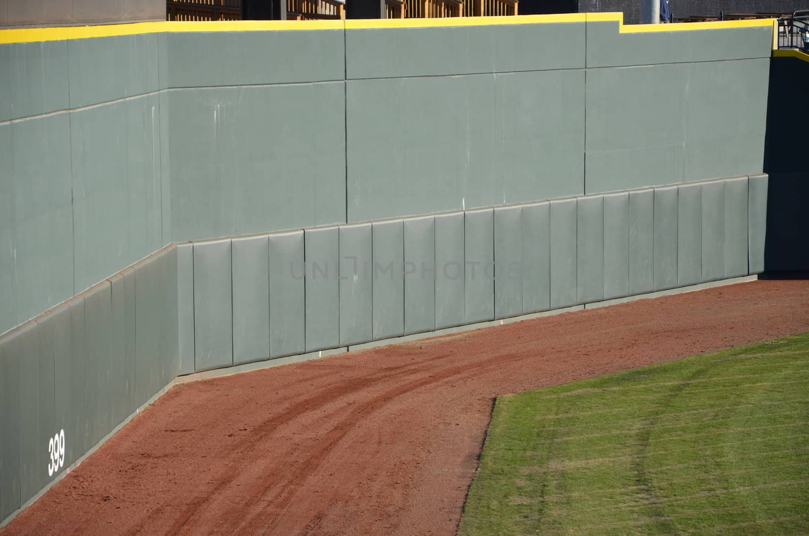 The wall at a baseball stadium. A high green fence