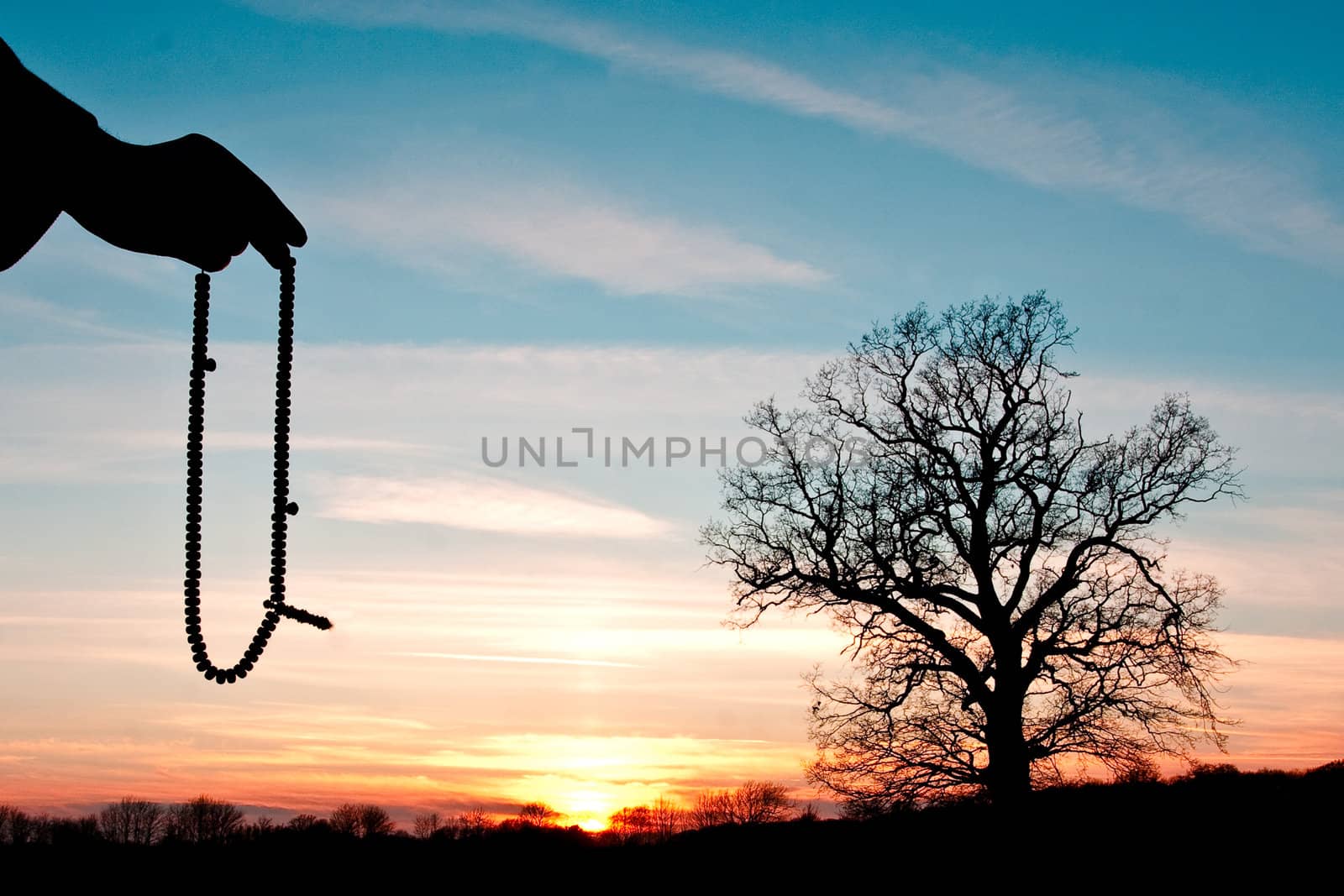 hand holding beads against a sunset scene