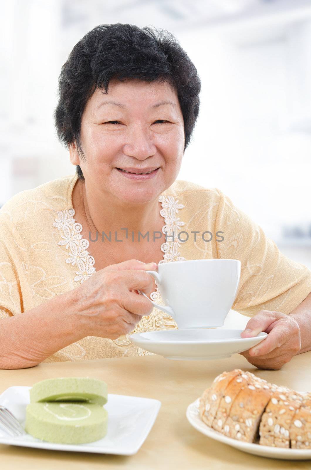 Happy Asian senior woman having breakfast at home