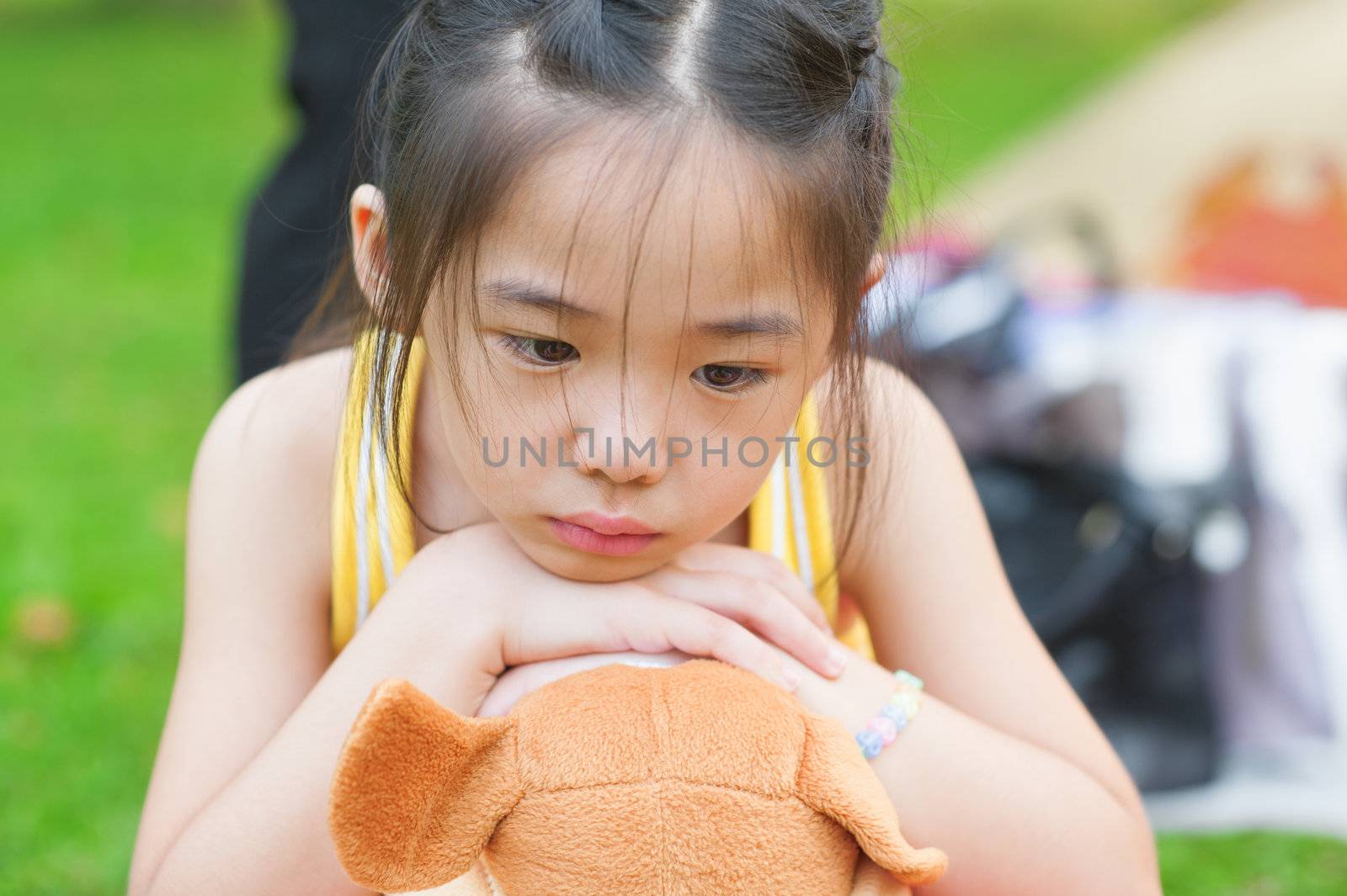 Outdoor upset Asian child. Little girl showing her unhappy face.