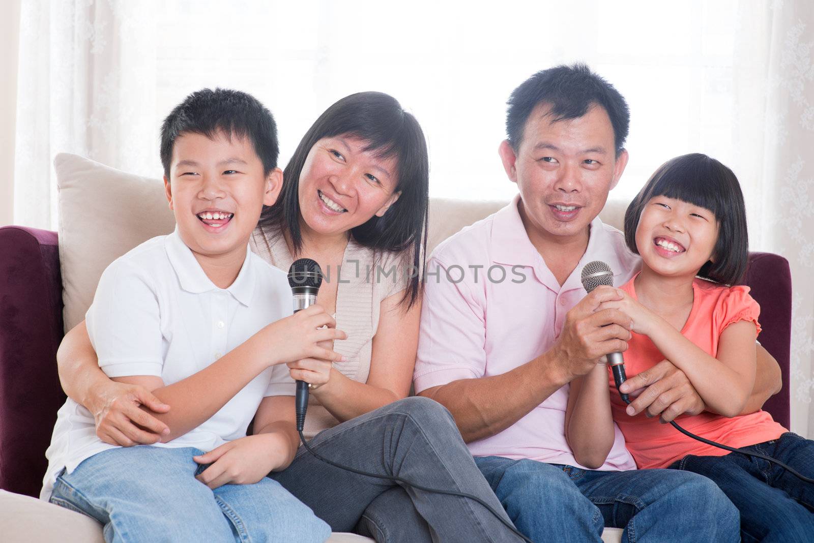 Family at home. Portrait of a happy Asian family singing karaoke through microphone in the living room