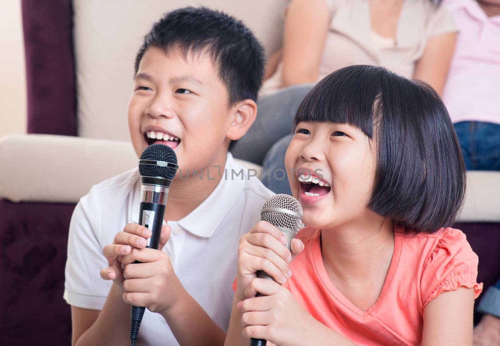 Family at home. Portrait of a happy Asian children singing karaoke through microphone in the living room