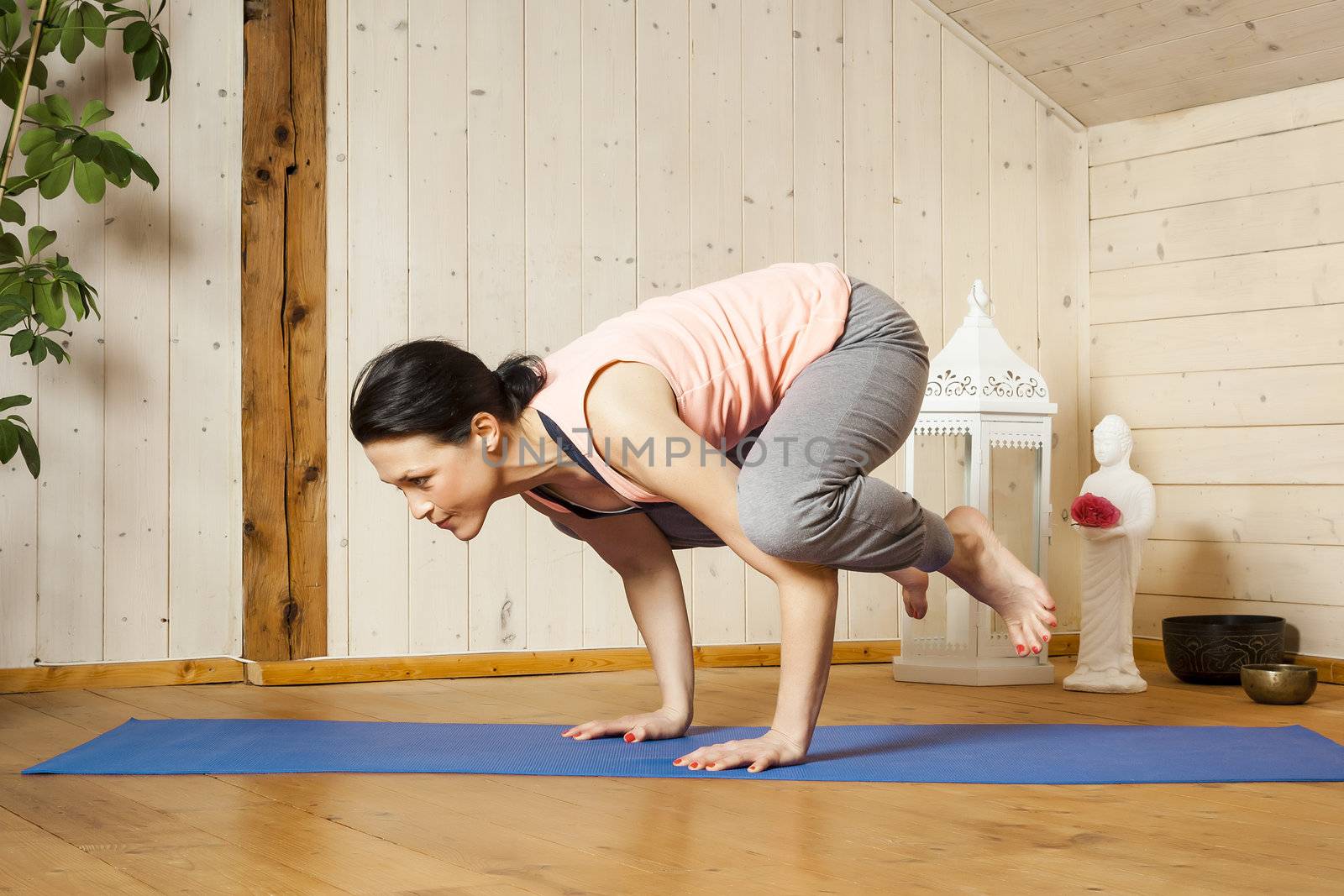 An image of a pretty woman doing yoga at home - crow