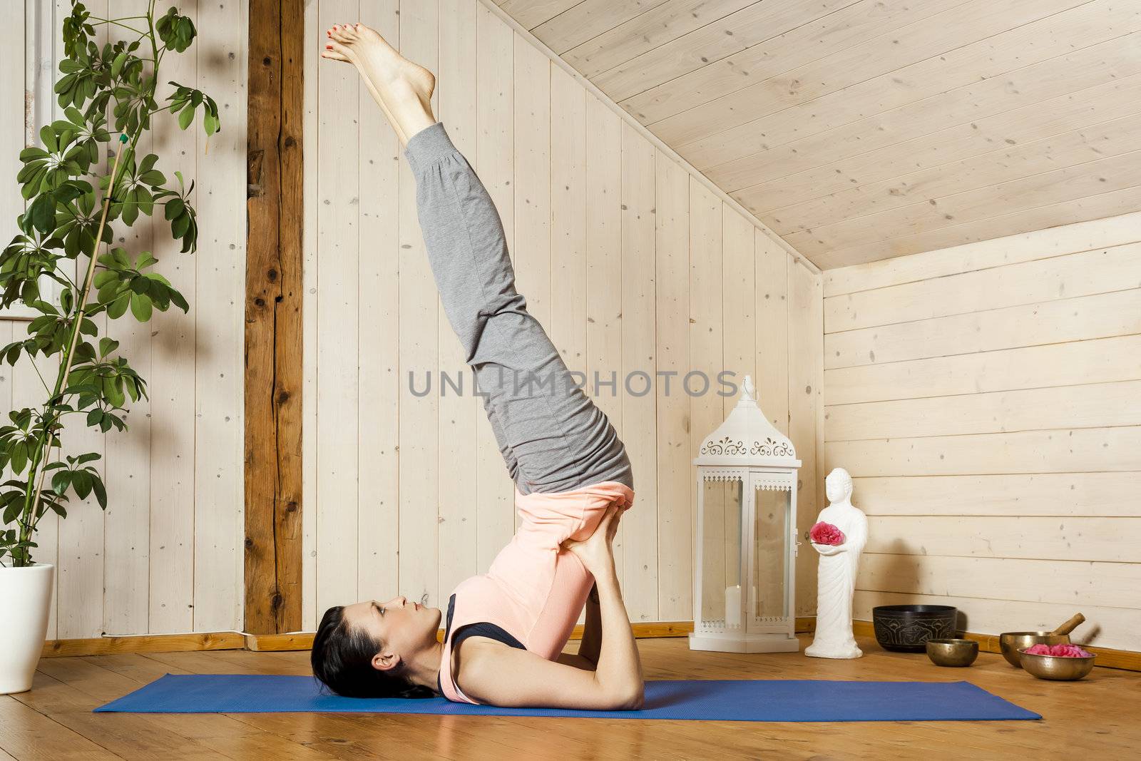 An image of a pretty woman doing yoga at home - Salamba Sarvangasana
