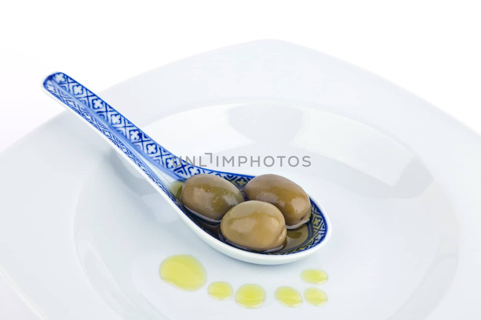 Olives on  spoon and olive oil isolated on white.