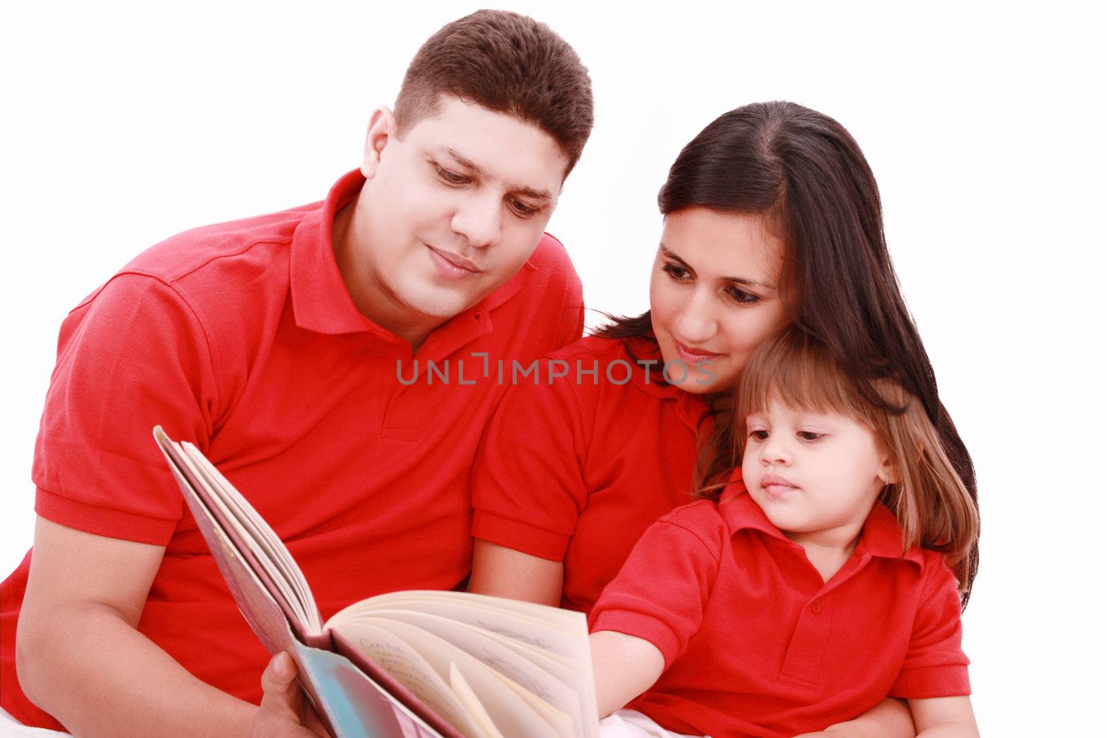 Family sitting on floor reading book at home