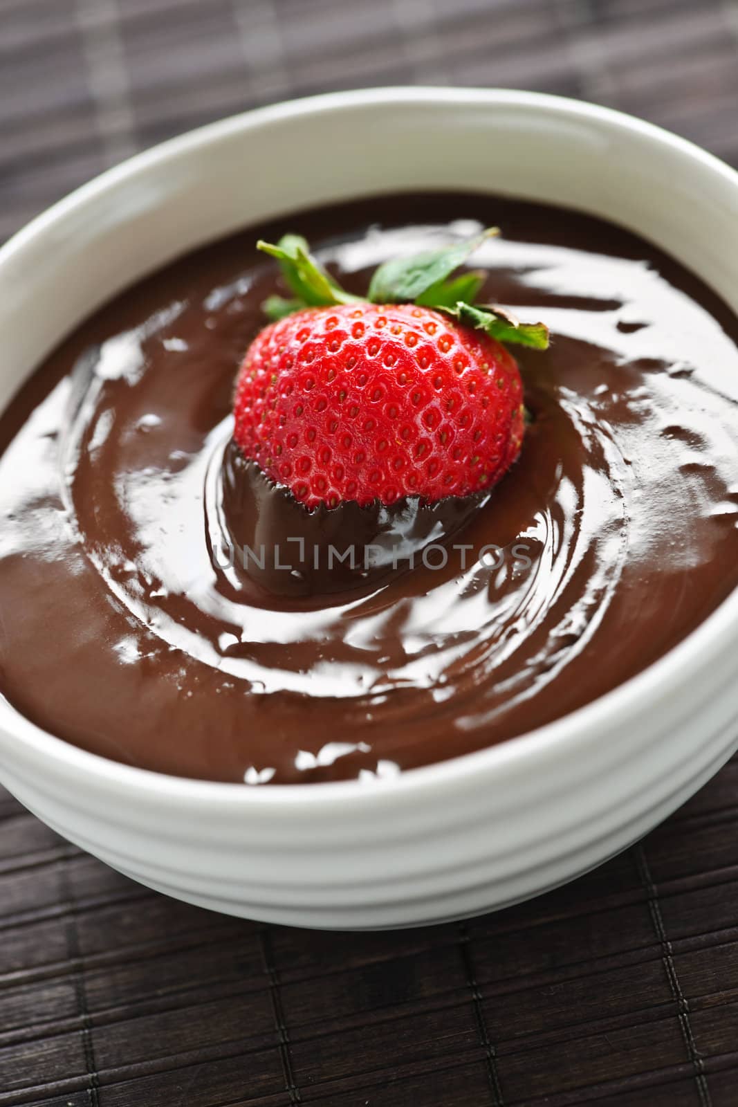 Fresh strawberry dipped in melted chocolate in bowl