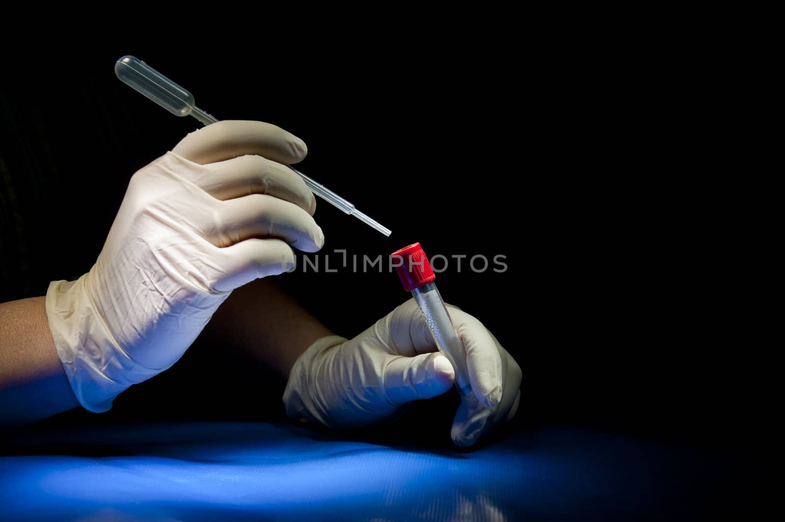 Hands in white gloves hold pipette and tube